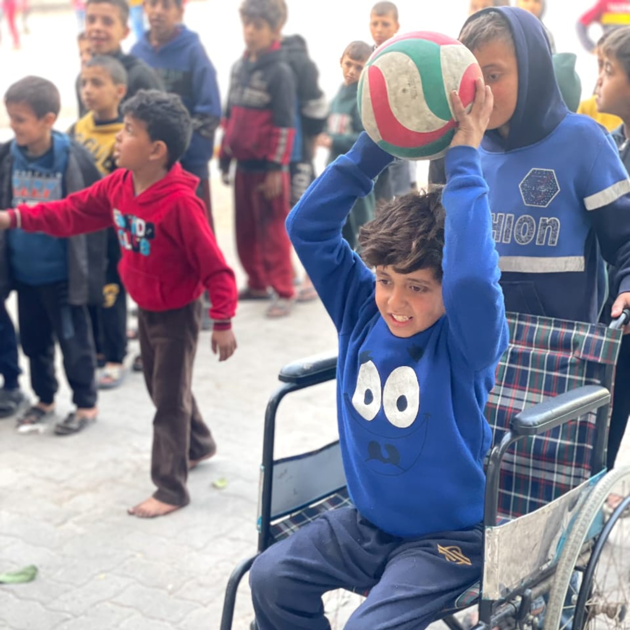 Young boy in wheelchair in Gaza City throws soccer ball in AFSC-organized recreation event