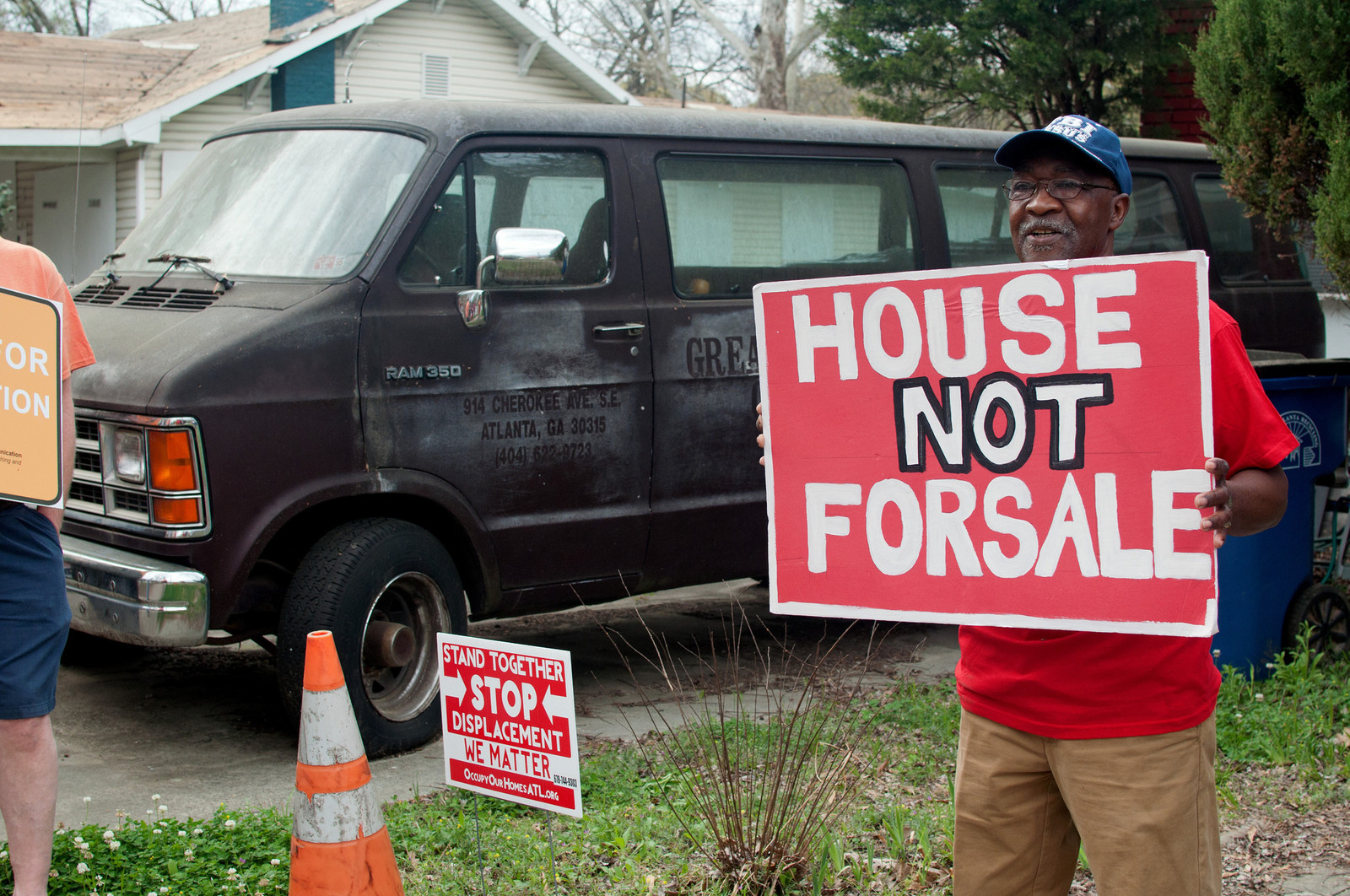 elder holding a sign in front of a van that reads