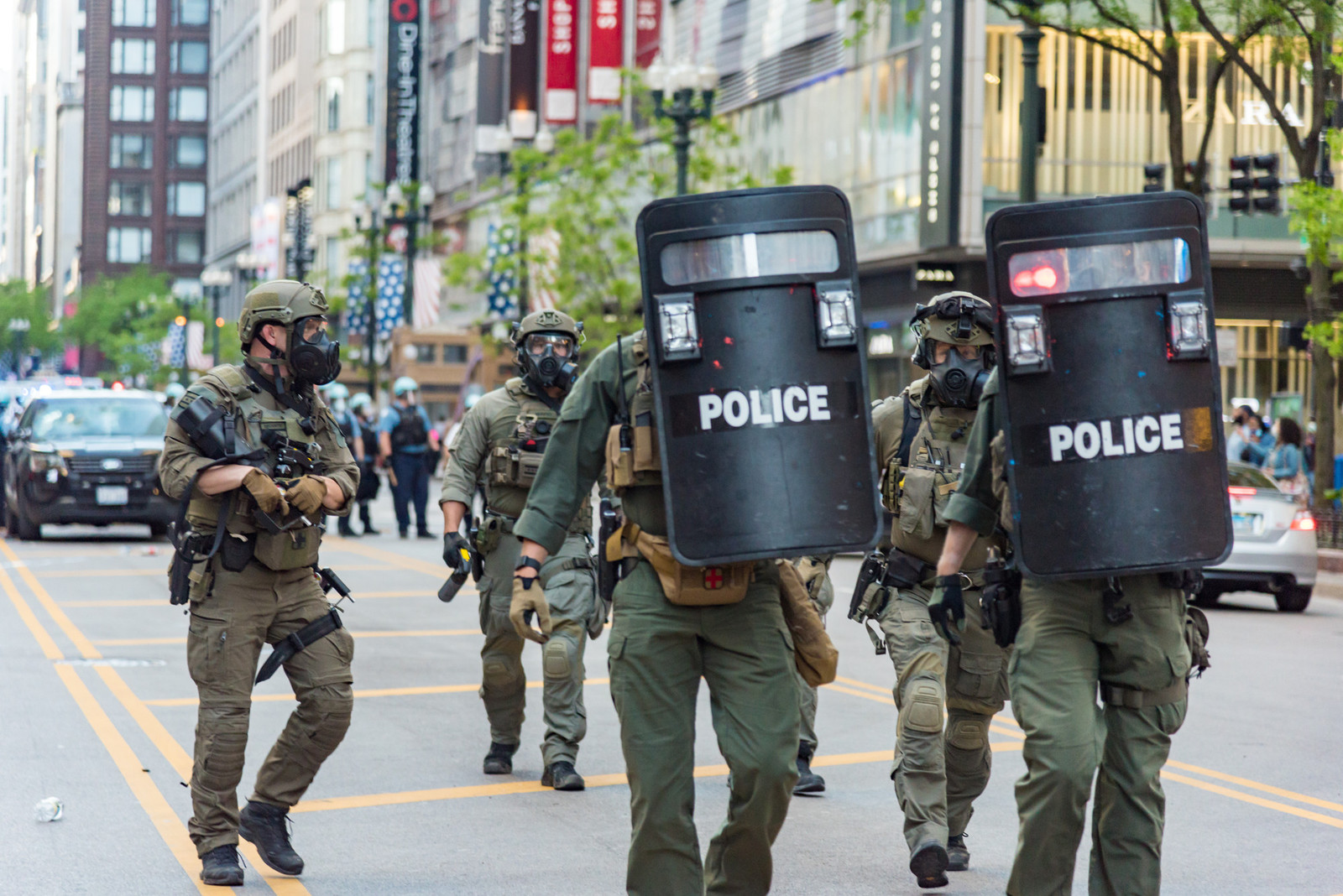 a group of five police offices wearing tactical gear and carrying shields walking down Michigan avenue in Chicago 