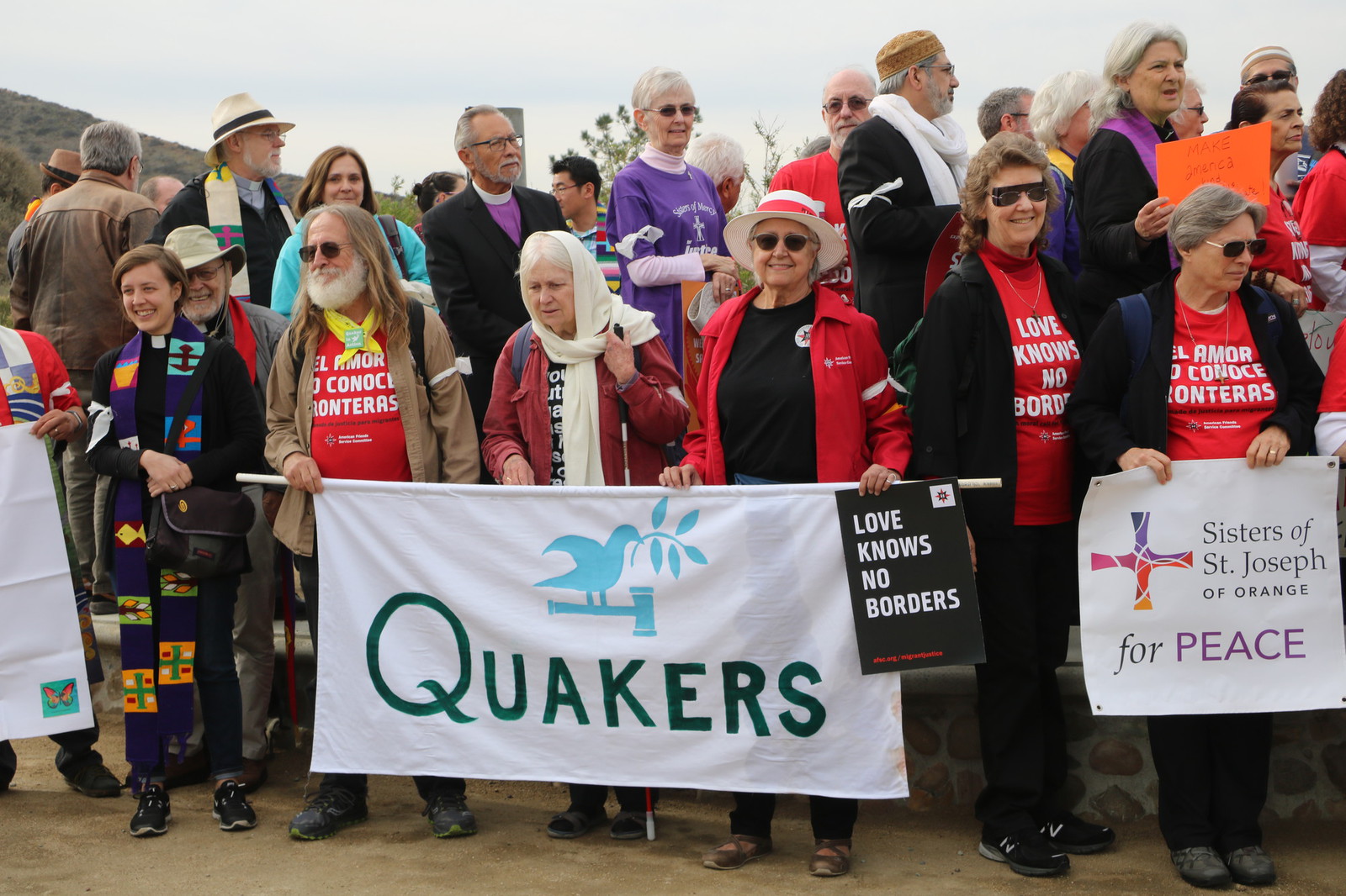 large group of people holding up a sign that reads Quakers