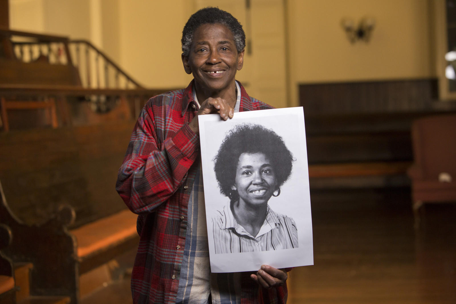 person holding up a portrait of themselves when they were younger
