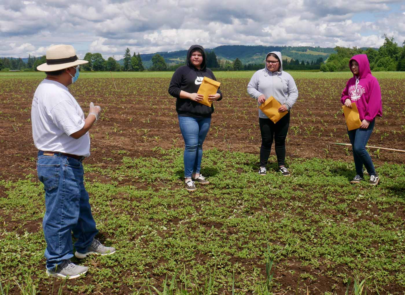 A community organizer giving information packets to farmworkers in a field