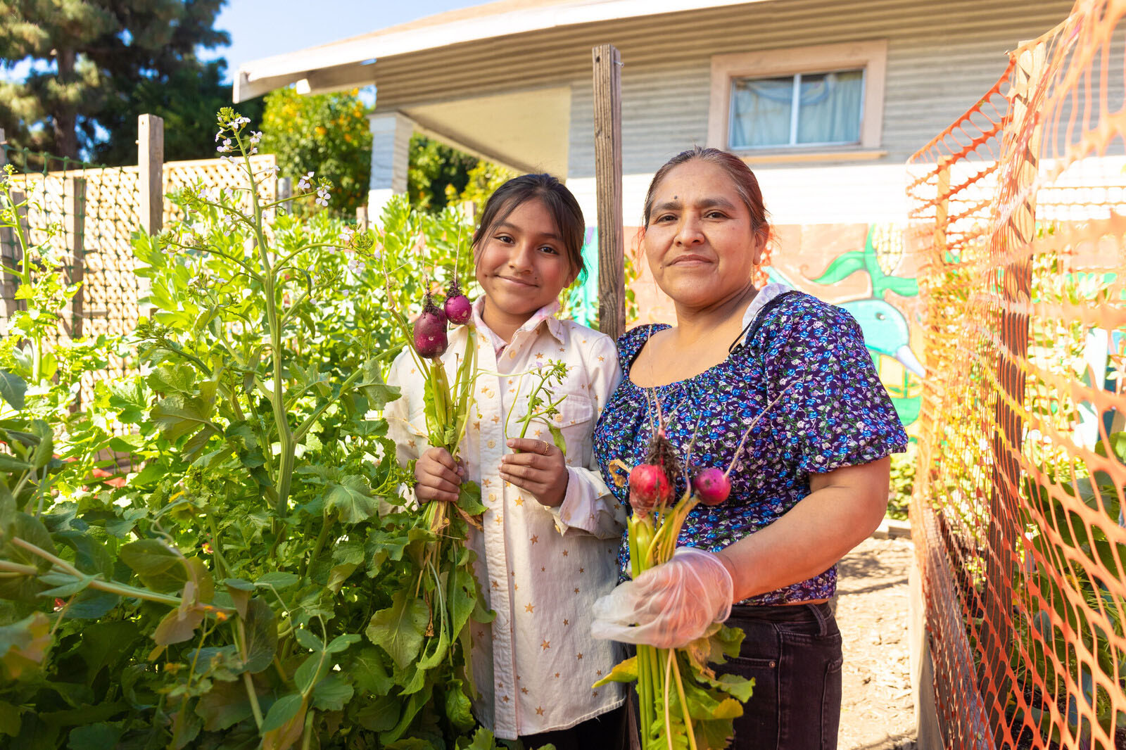 A woman and daughter standing in a garden holding radishes