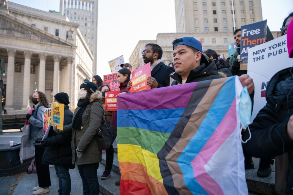 Person holds multicolored flag with crowd during protest