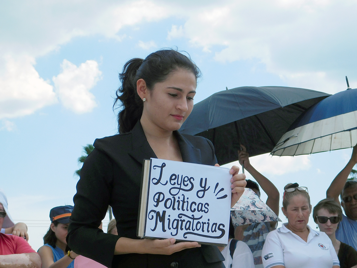 person holding sign at a protest with umbrellas in the background