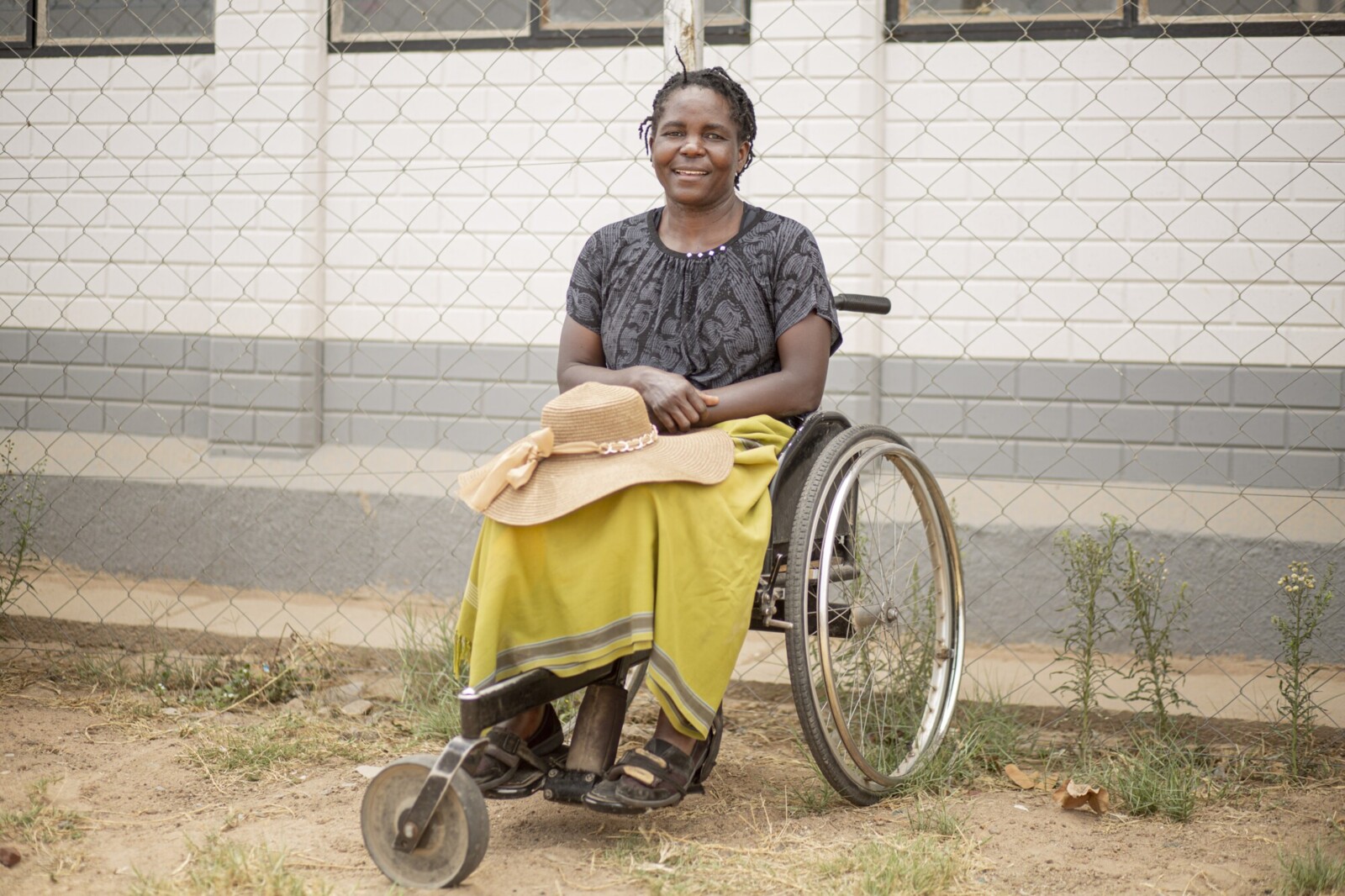 A smiling woman sitting in a wheelchair outdoors