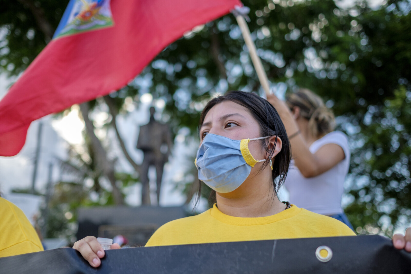 person wearing a mask with a Haitian flag in the background