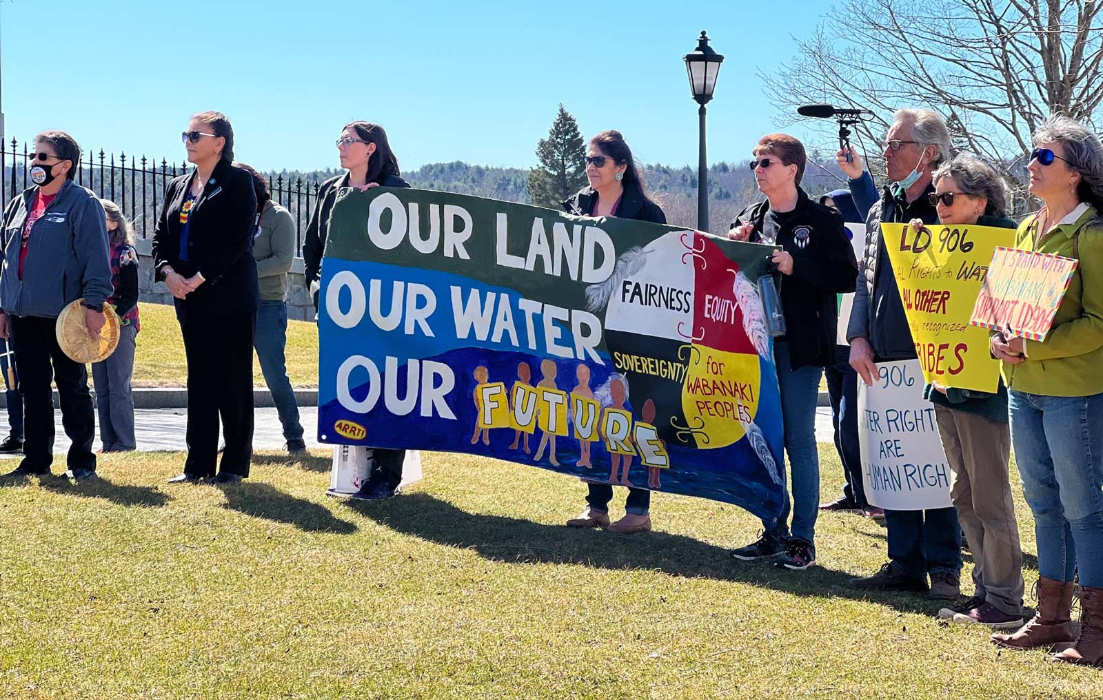 A group of people stand in a line, several holding a banner that says 