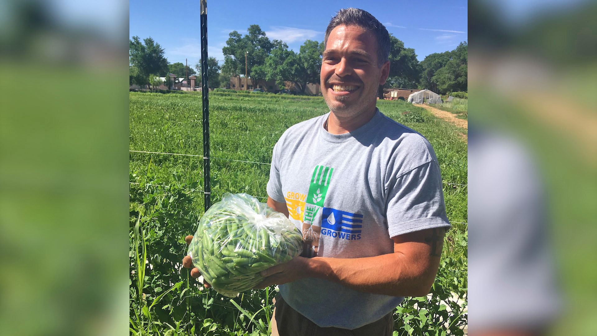 Smiling man standing in a farm holding a bag of produce