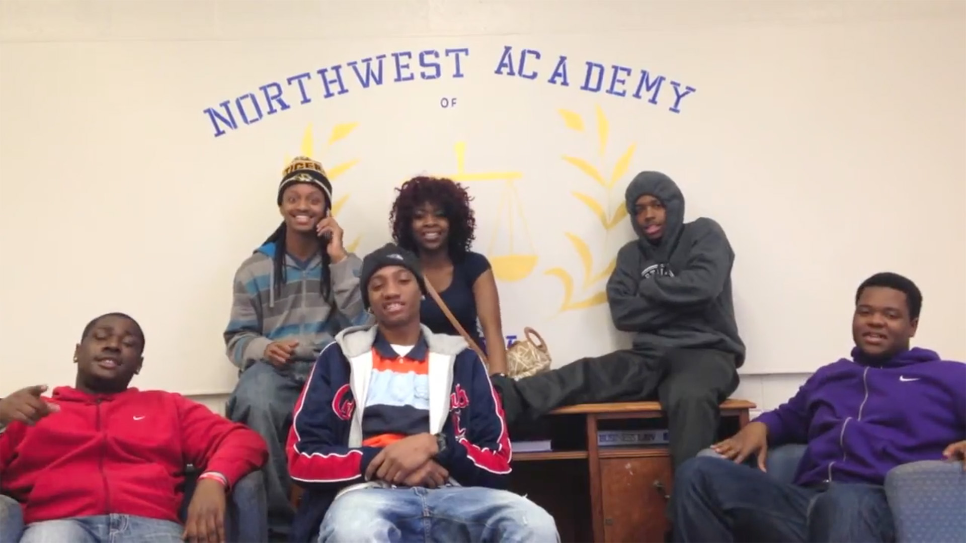 Six youth sitting together smiling at the camera at Northwest Academy