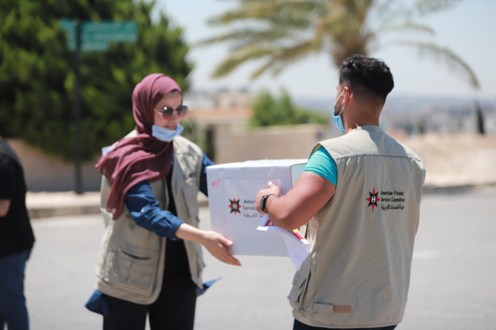 Person handing off a box of supplies to another person