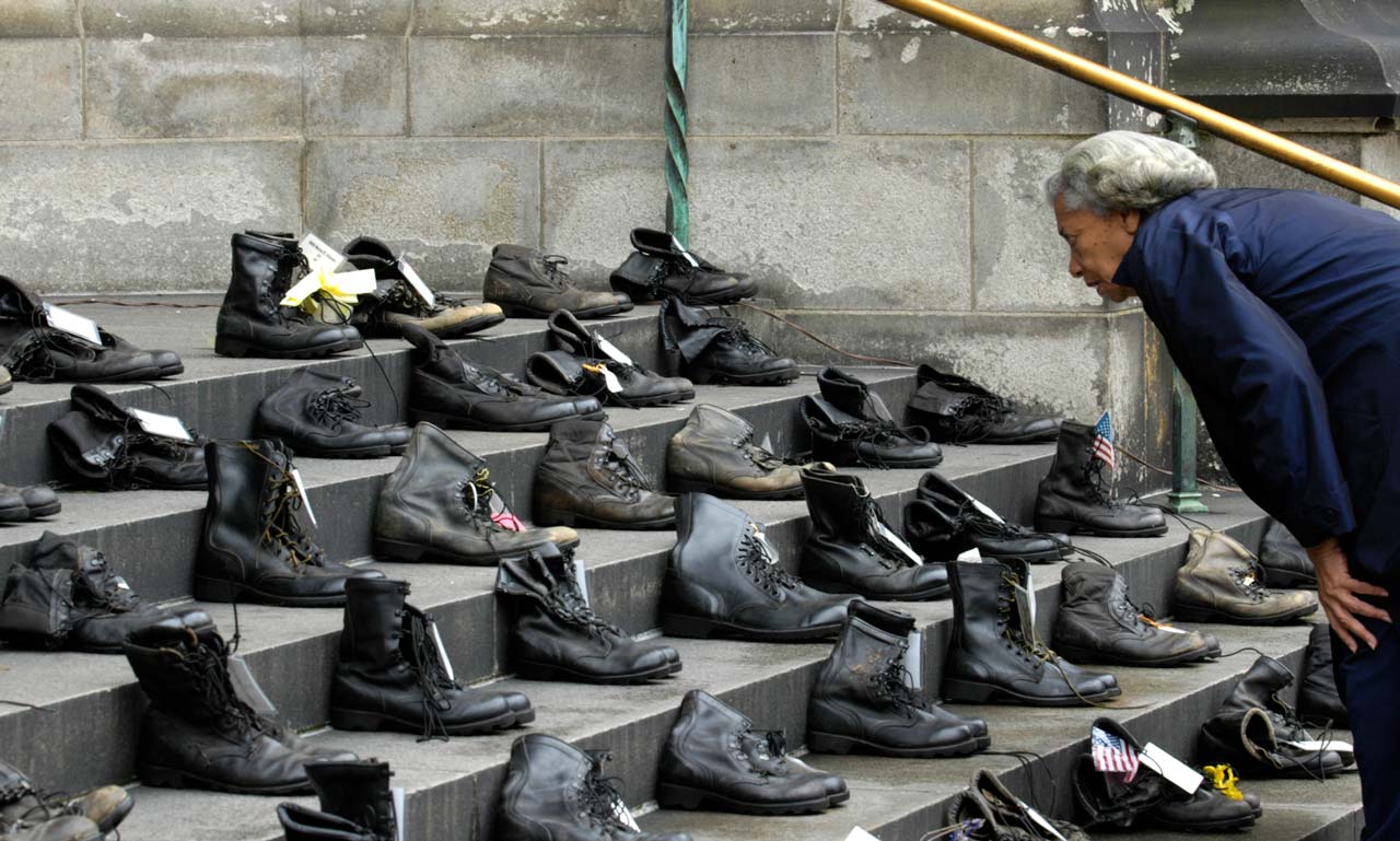 Person looking at dozens of pairs of boots arranged on steps.