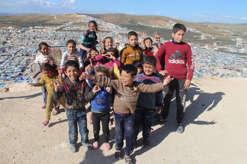 Group of kids smile and pose on a hillside