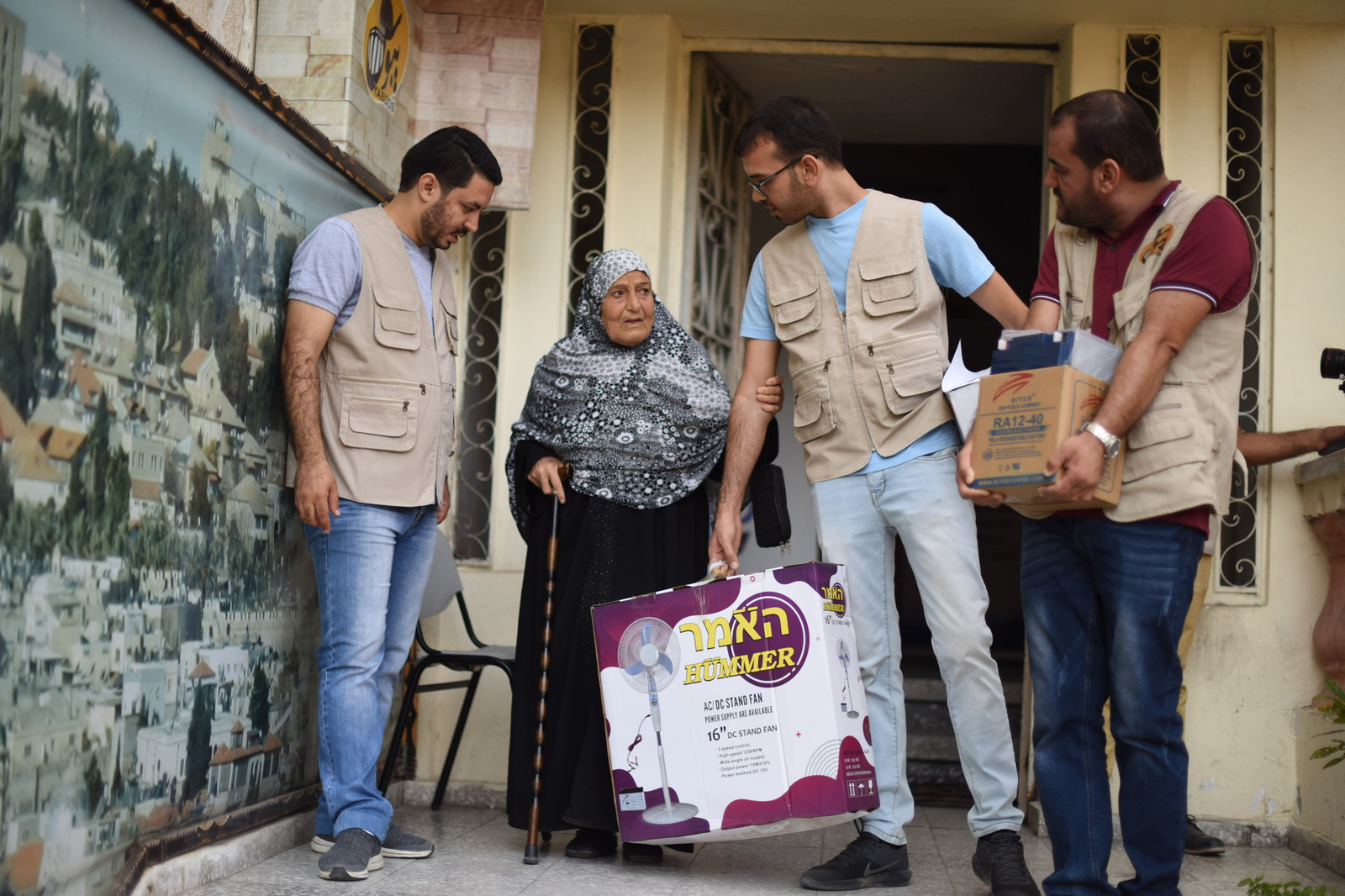 3 people in AFSC vests stand next to a senior holding a can 