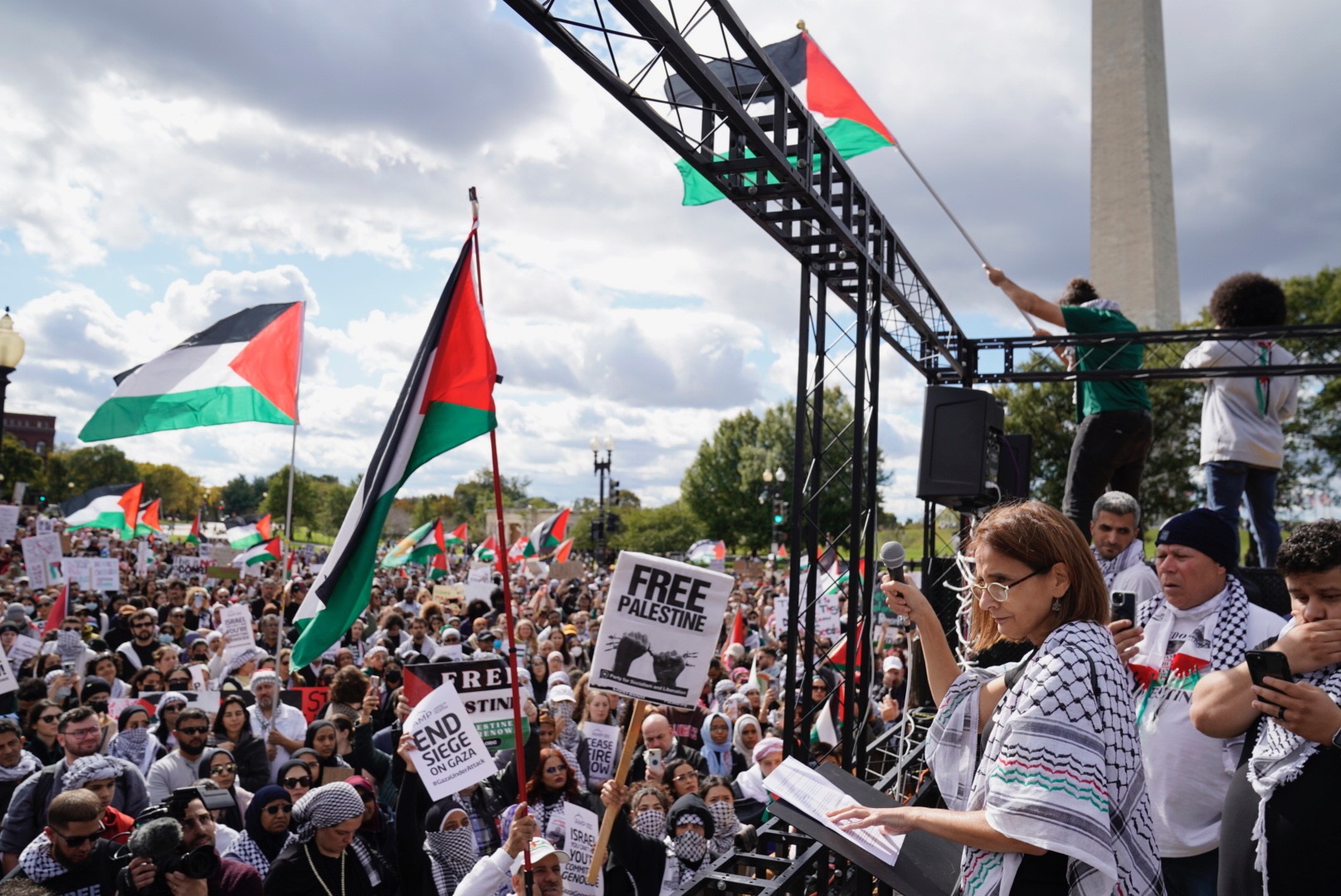 Woman with mic on stage speaks to crowd in front of Washington monument