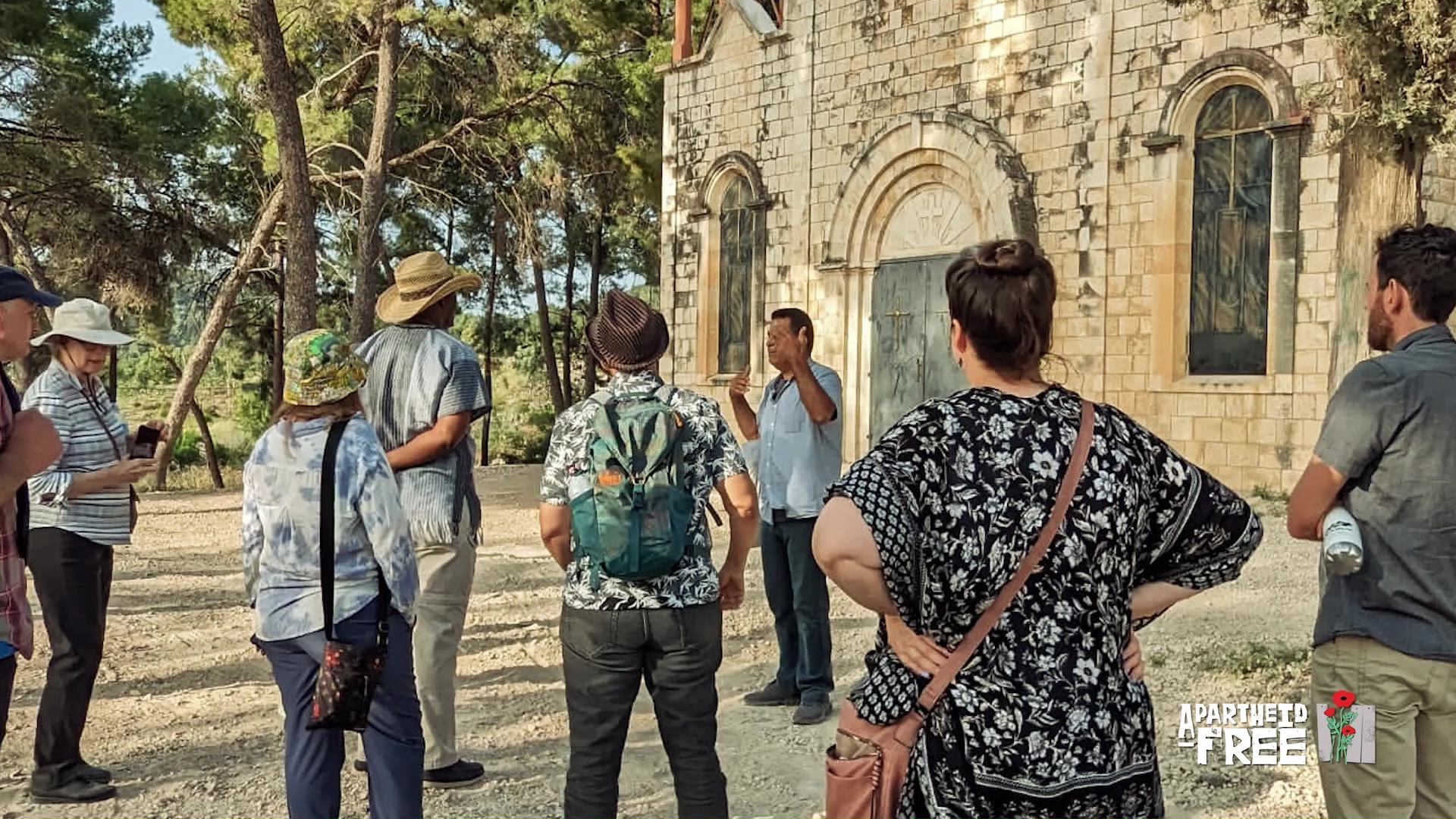 A group of people standing around a man presenting in front of a historical building