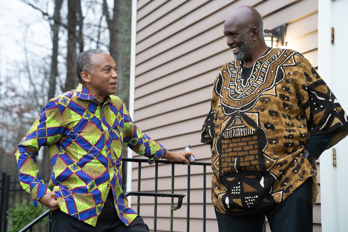 Two men in colorful shirts speak to each other outside