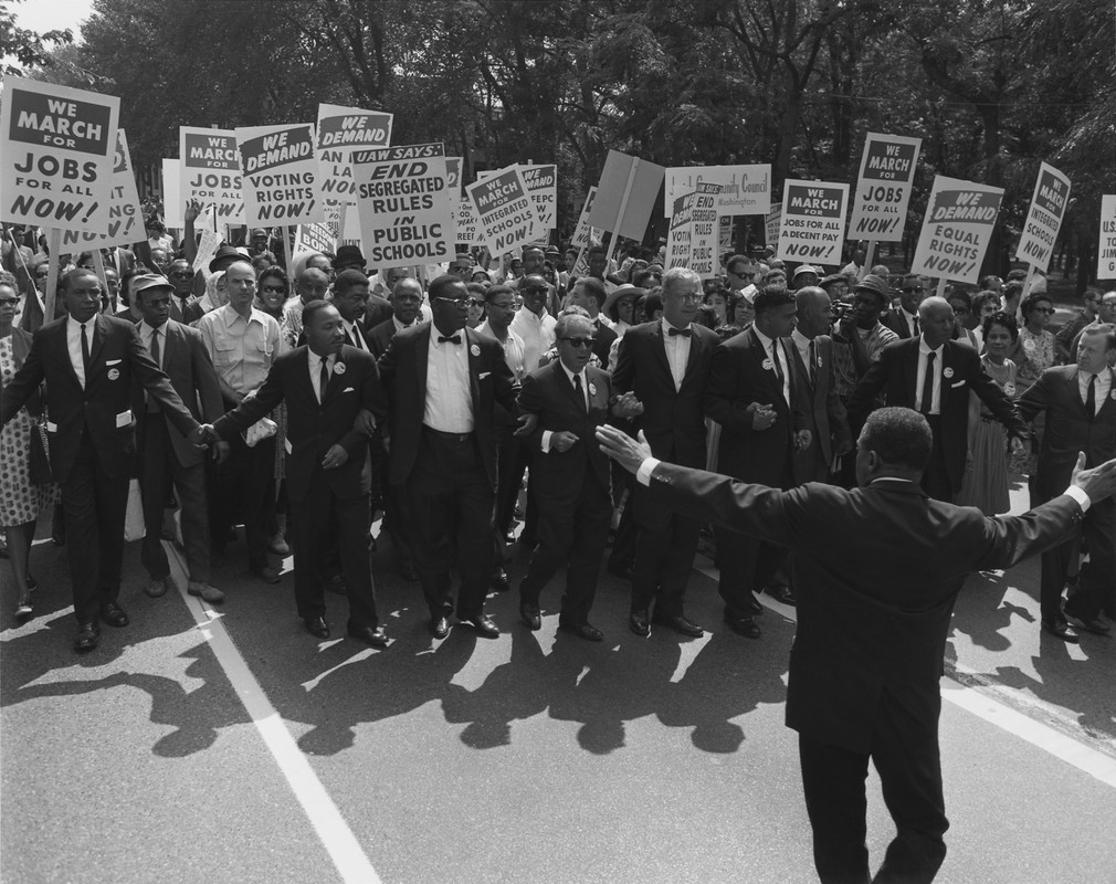 Black and white photo of crowd marching with signs