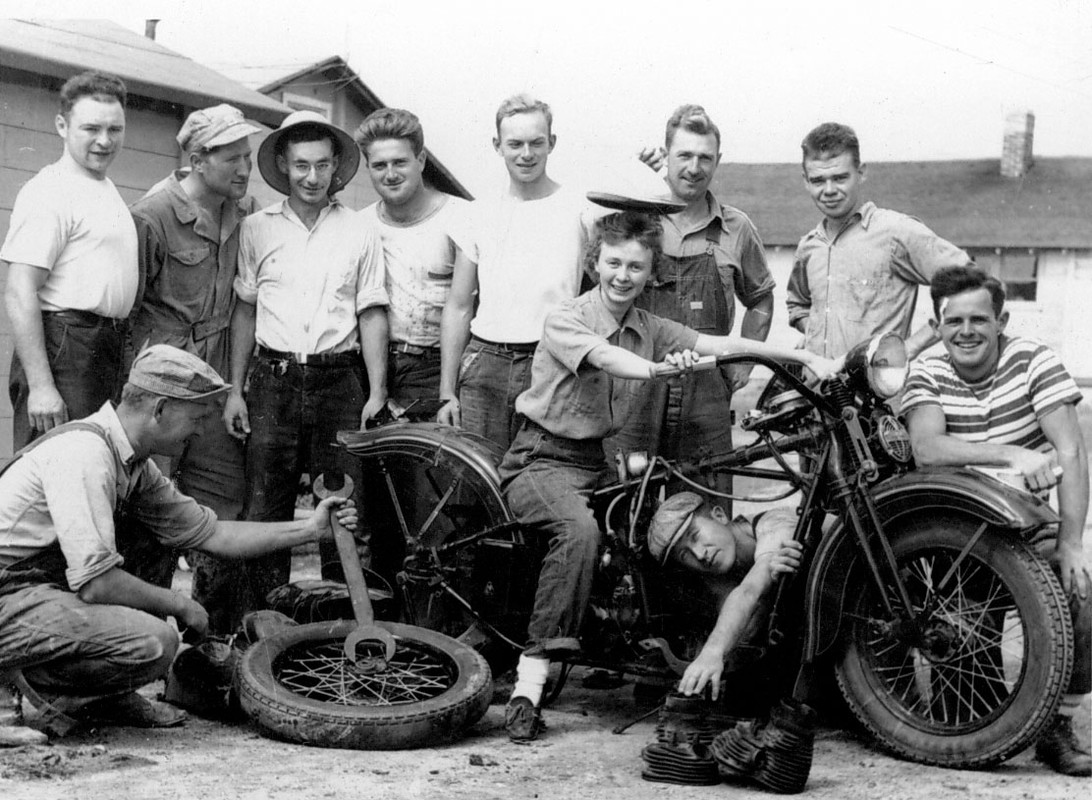 Group of people standing around an old motorcycle
