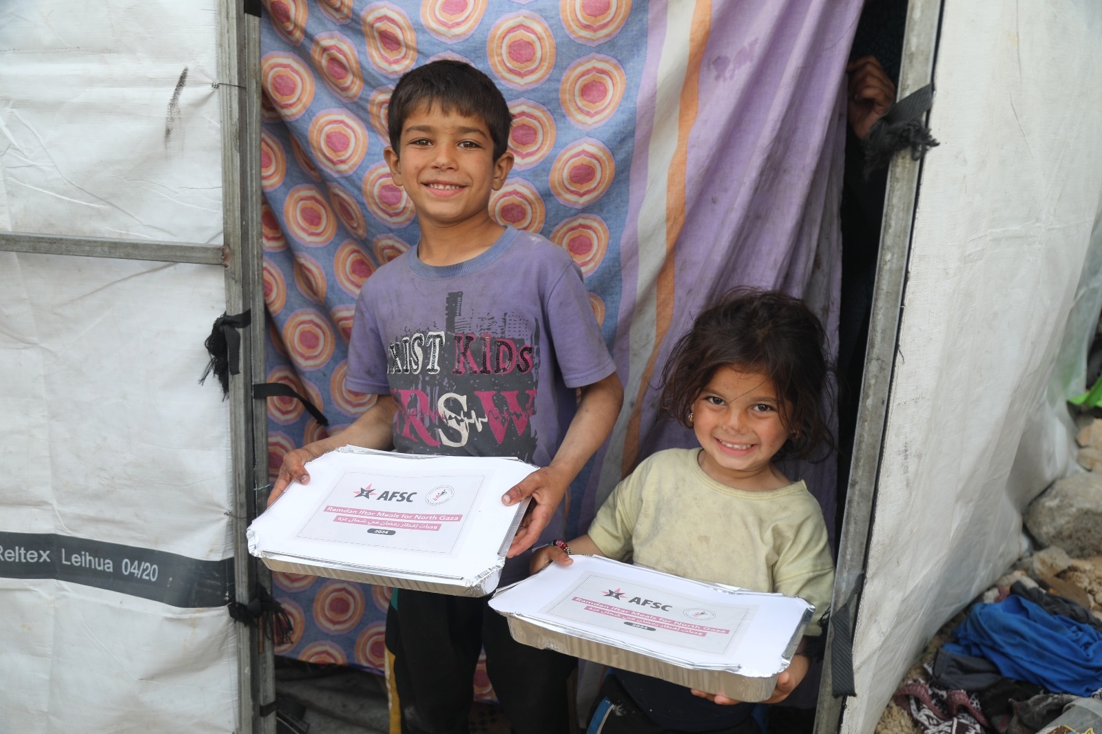 2 children smile and hold trays of food 