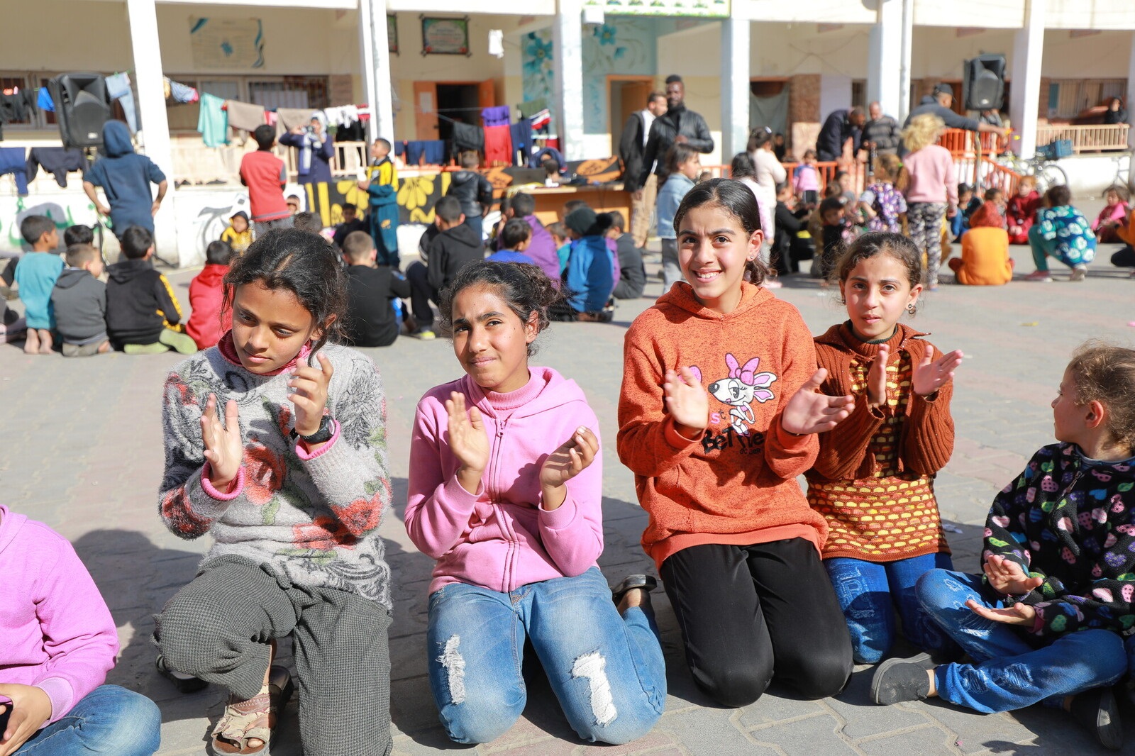 4 children kneeling on the ground clapping hands