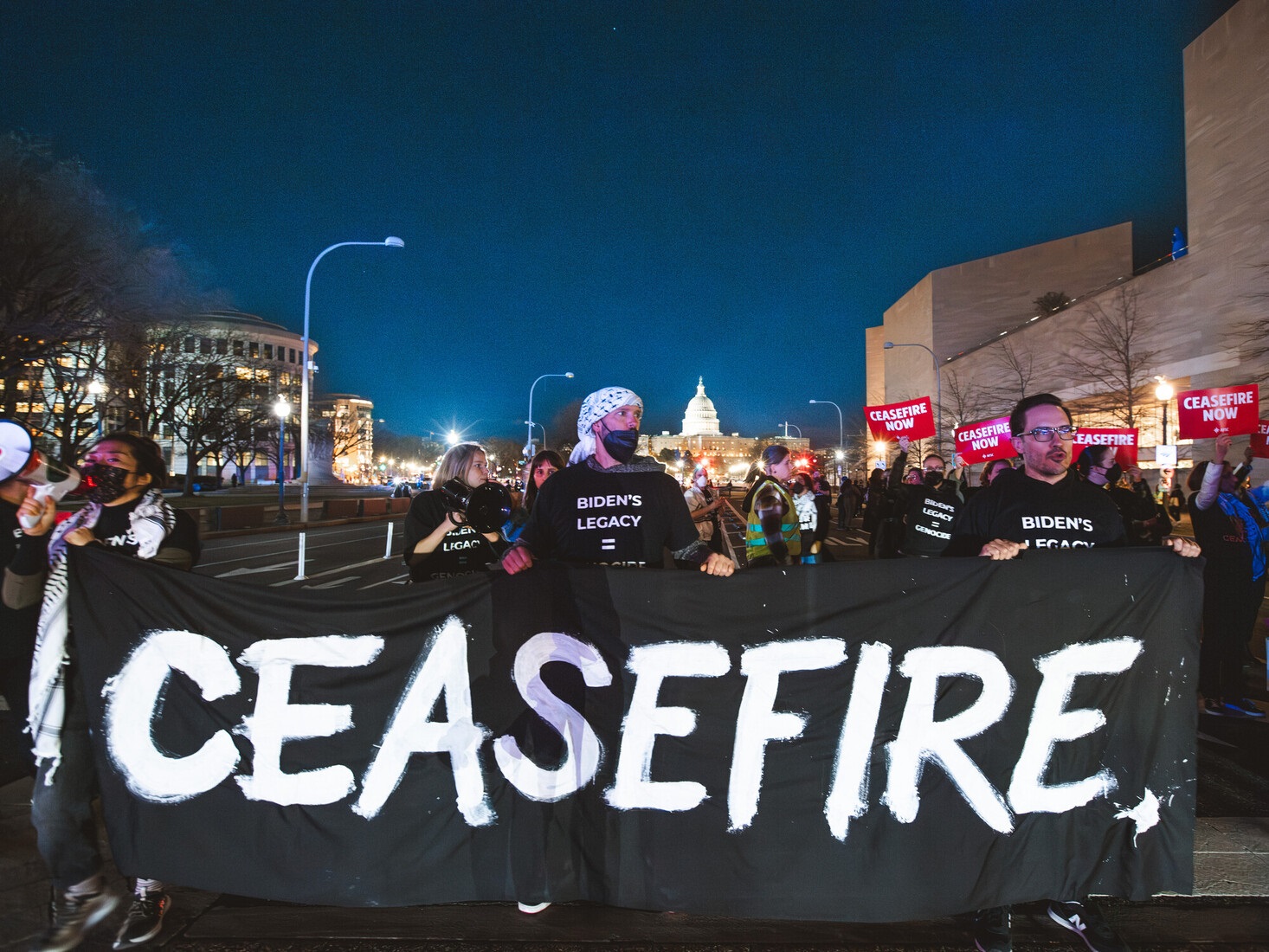 Group of people hold a black banner that says 