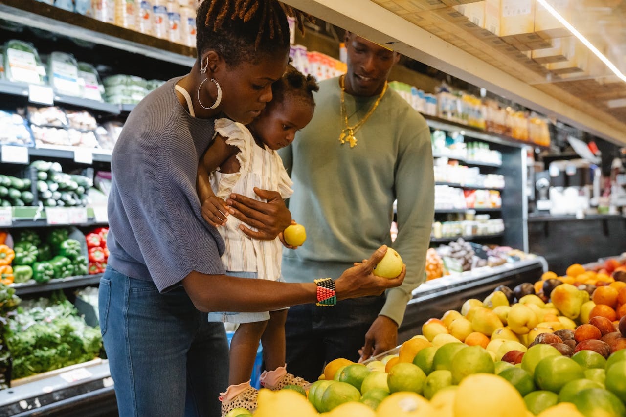 Woman and man hold shop for fruit with toddler