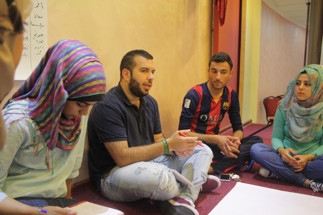 Group of youth sitting on the floor with paper and pens