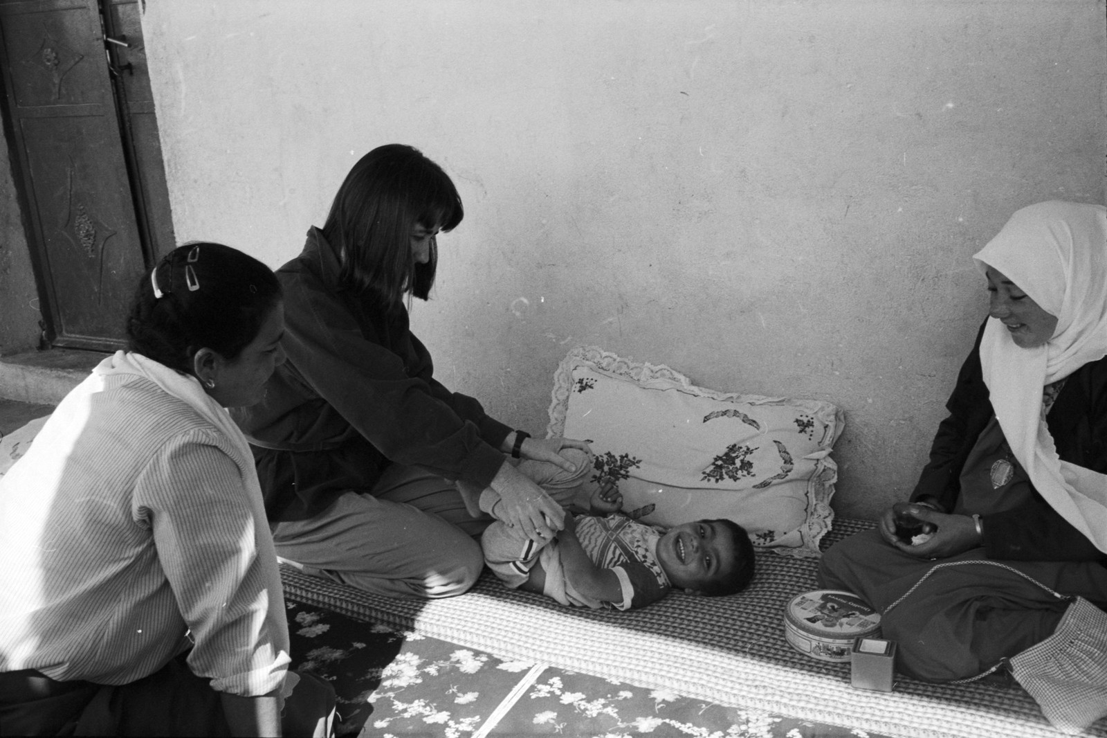 Three women attend to a young child on the floor