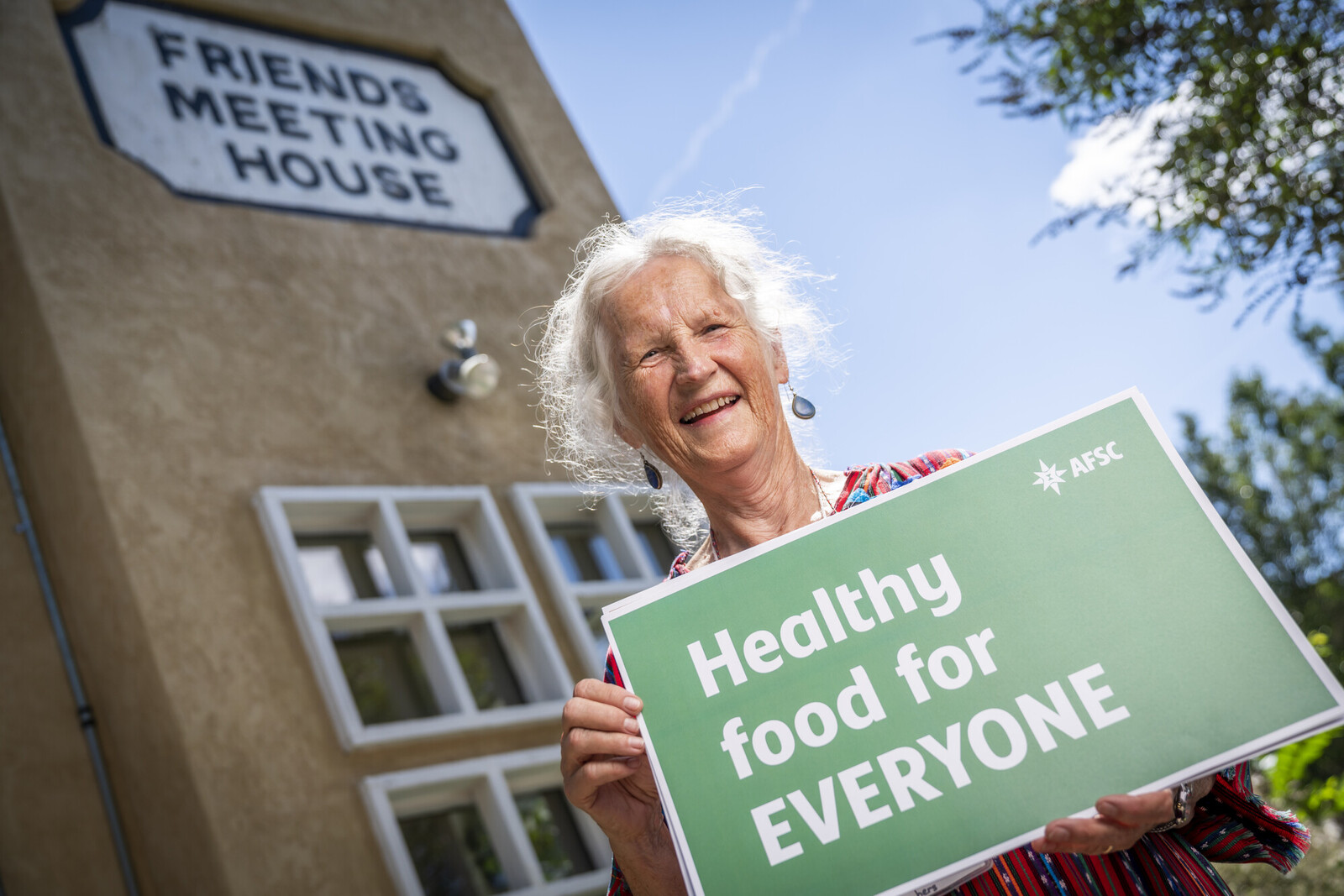 Woman holding a sign saying Healthy Food for Everyone