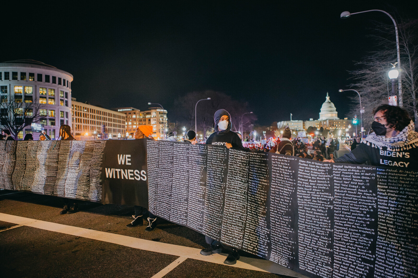 People holding a giant banner in front of the capitol building that says 