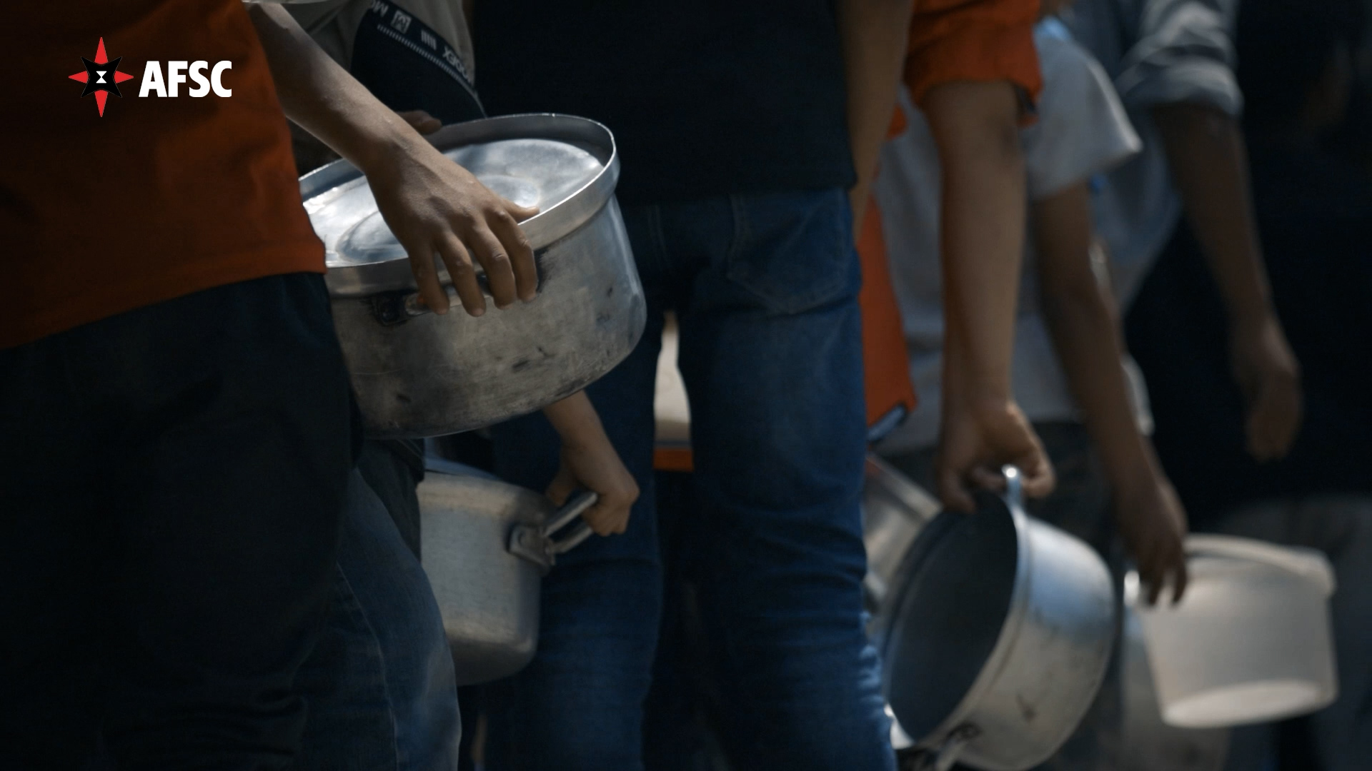 Row of children holding empty soup pots