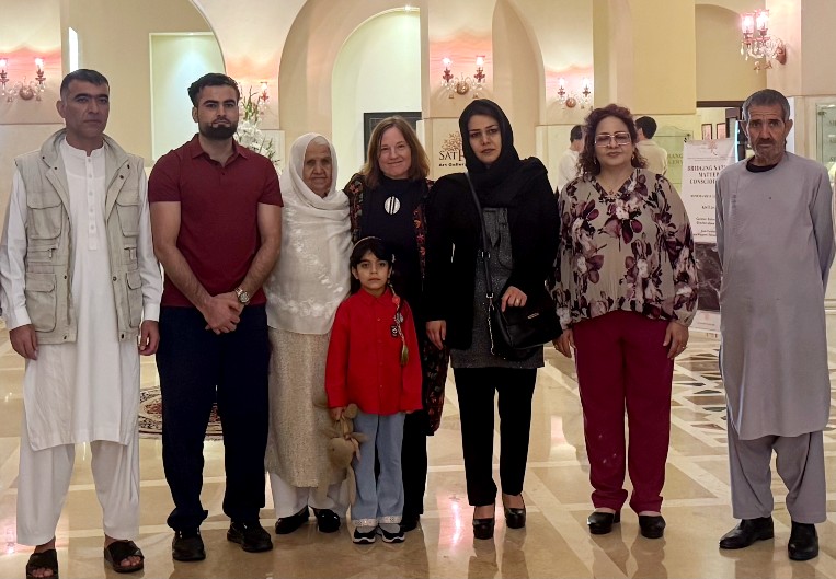 7 adults and a child stand in together in a group photo