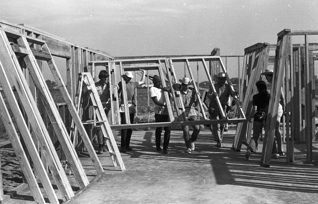Group of people assembling a house frame