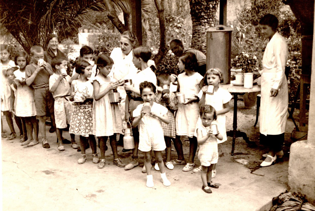 Black and white photo of children lining up to receive food