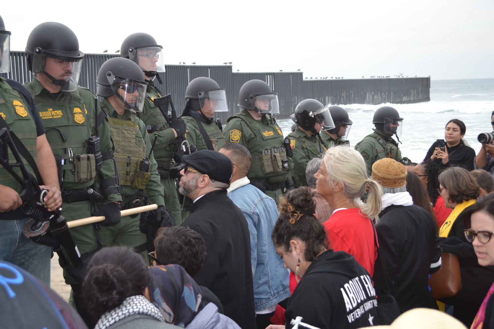 Activists kneel in front of armed border patrol agents