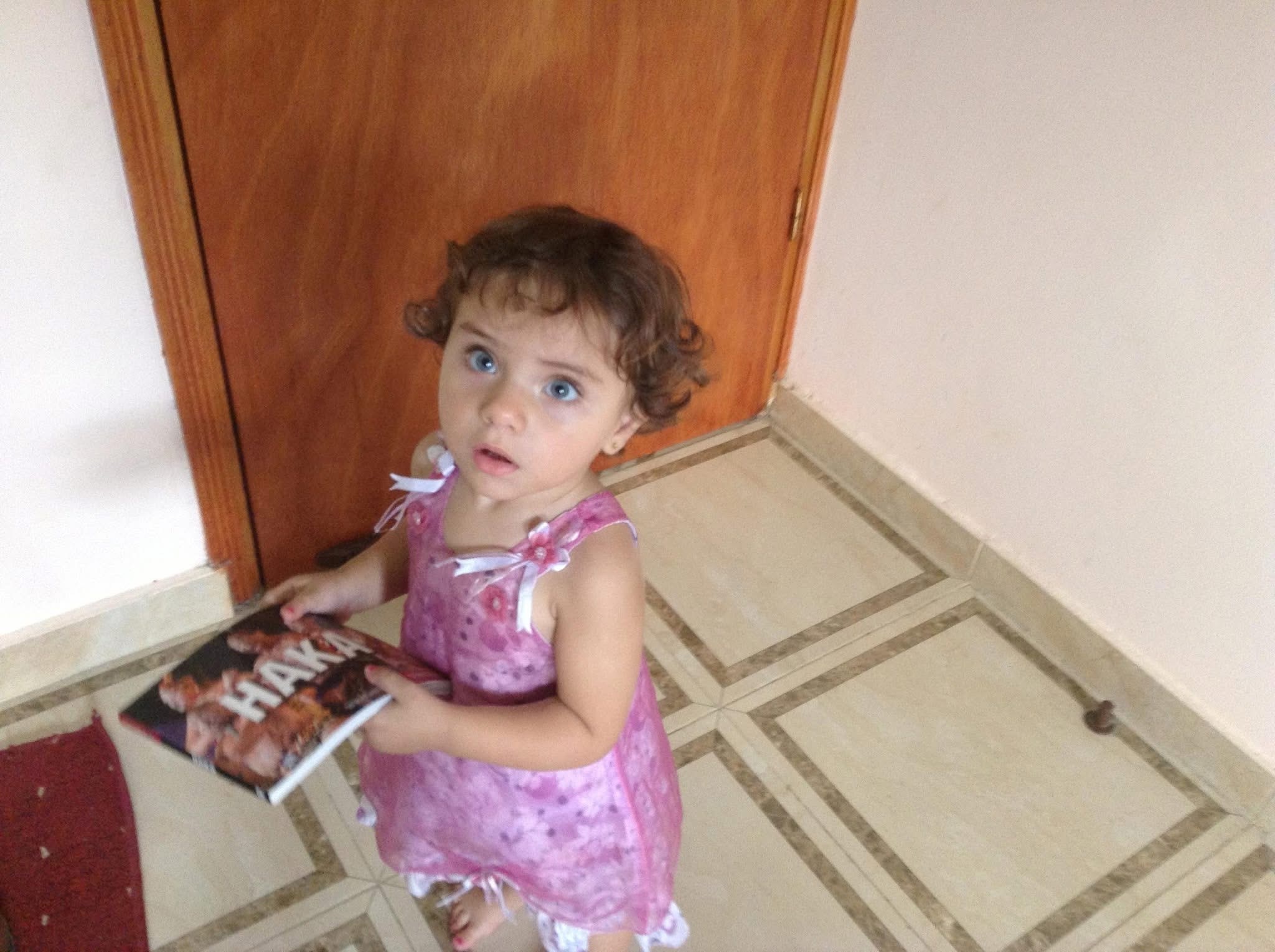 A child holds a book next to a closed door
