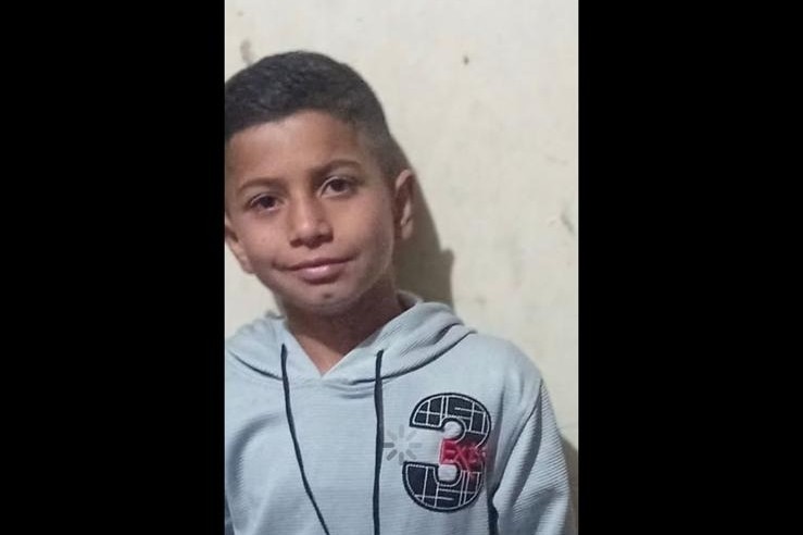 A boy in a hoodie looks at the camera
