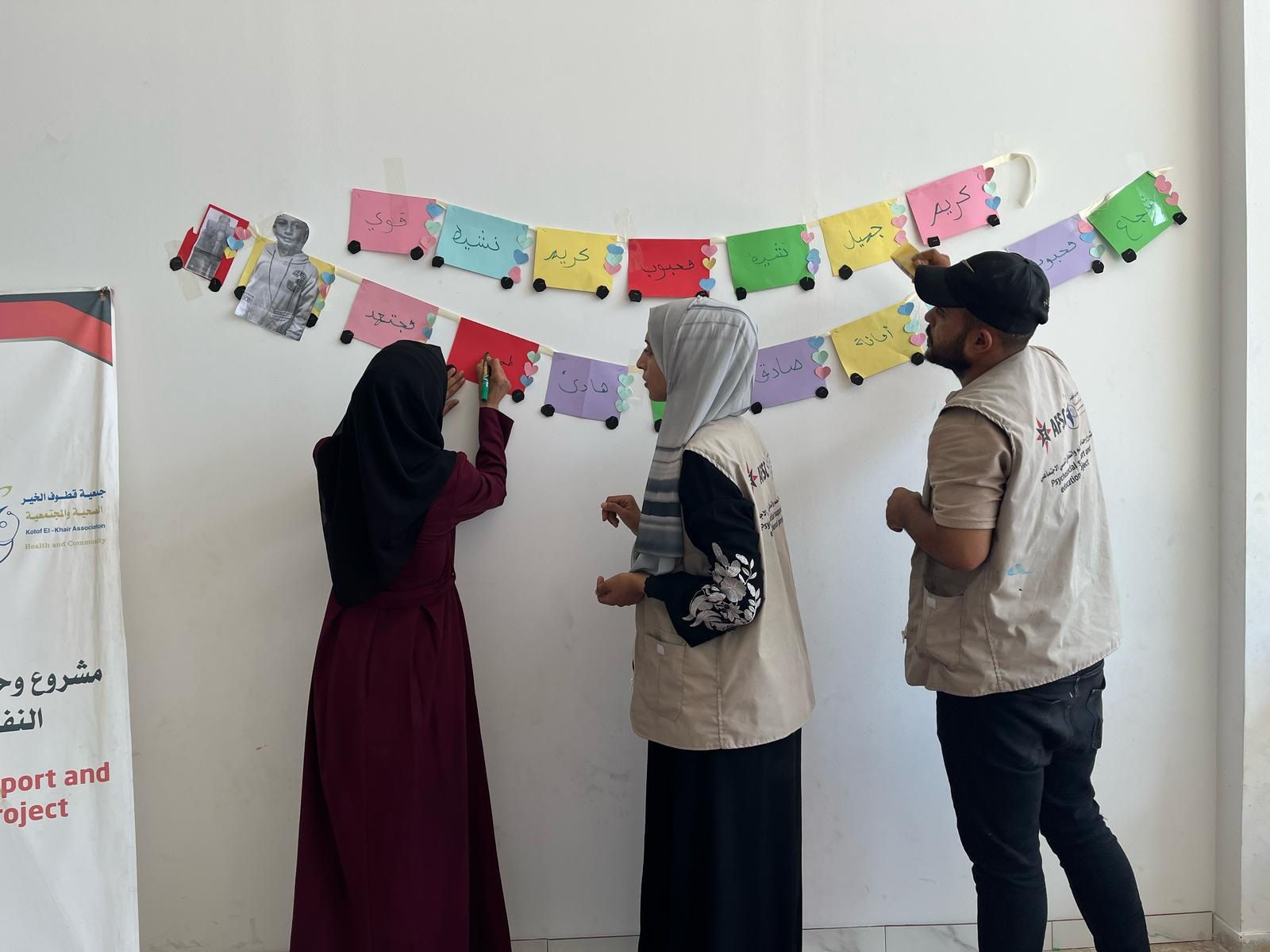 3 people look at a colorful banner on the wall 