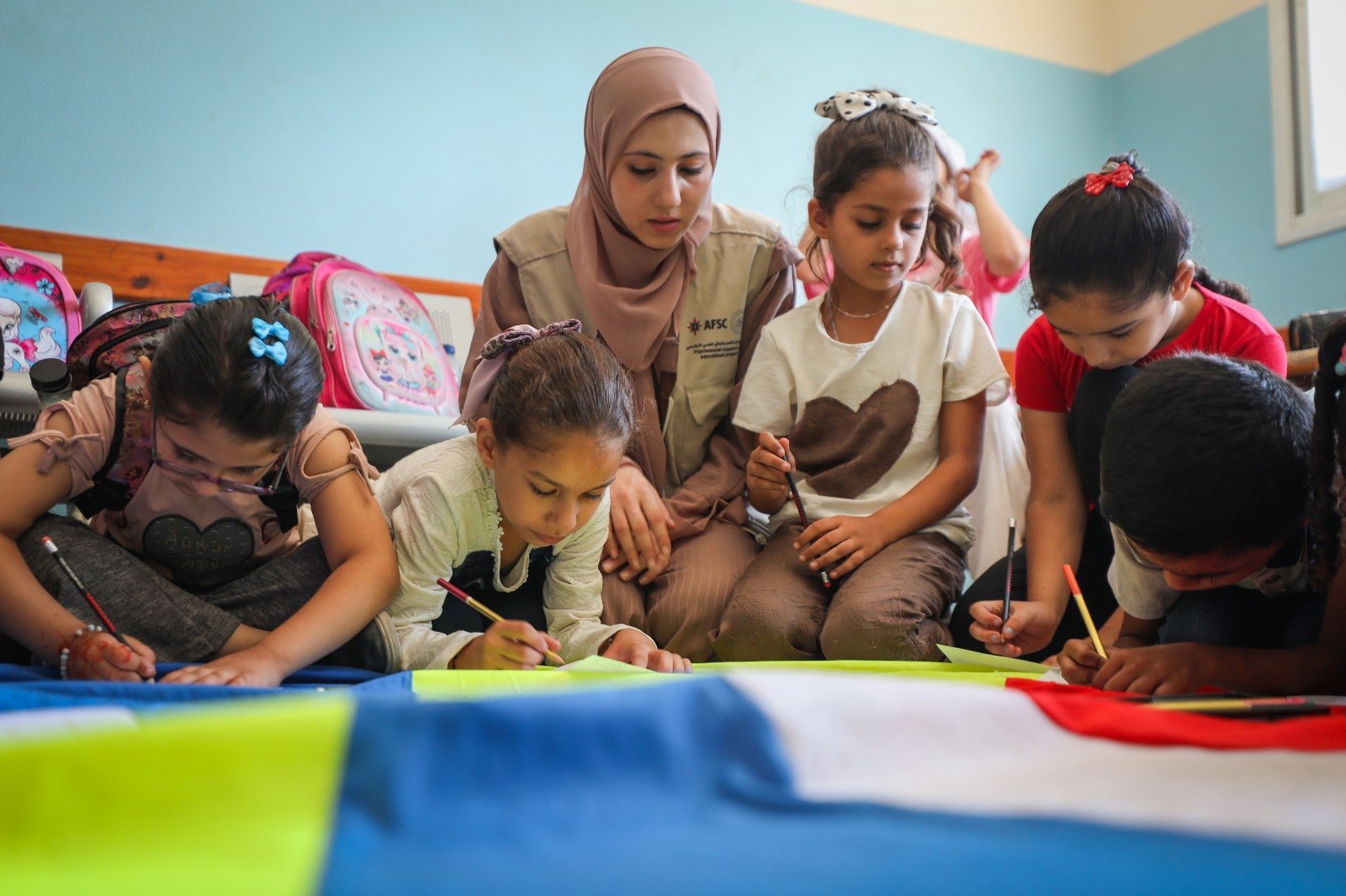 Children and an adult work on an activity together in Gaza