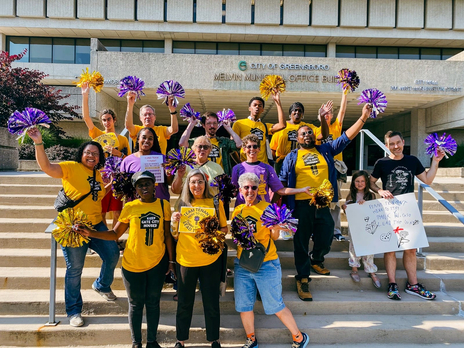 Image of a group of people on stairs in yellow shirts that say 'Keep Gate City Housed'