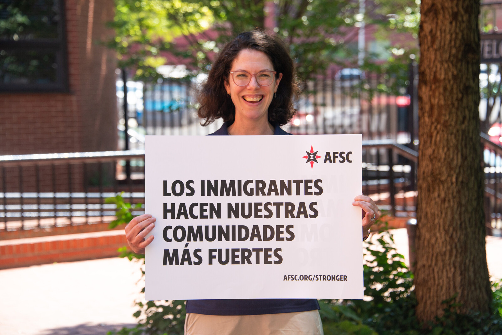 woman holding sign that reads los immigrants haven nuestras comunidades mas fuertes