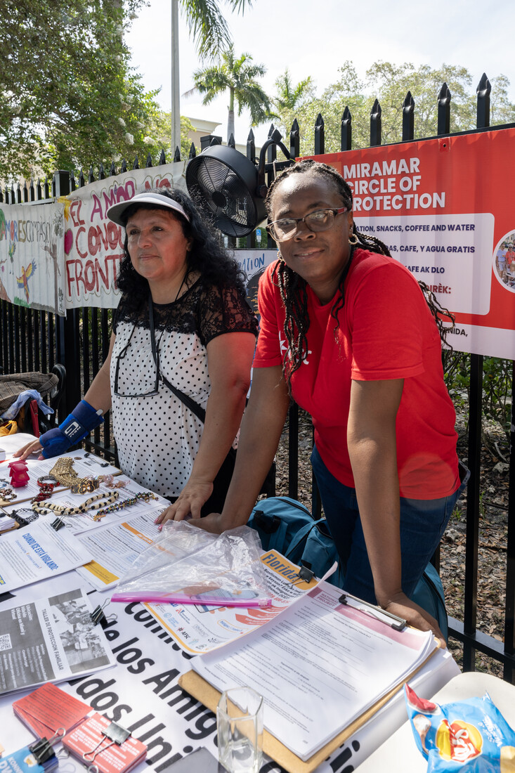 two people leaning over a table with papers, there is a gate behind them