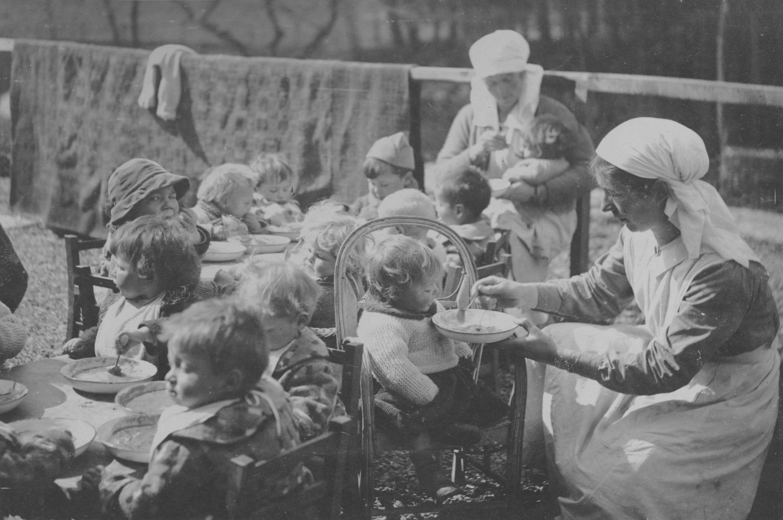 Young children being fed at a table.