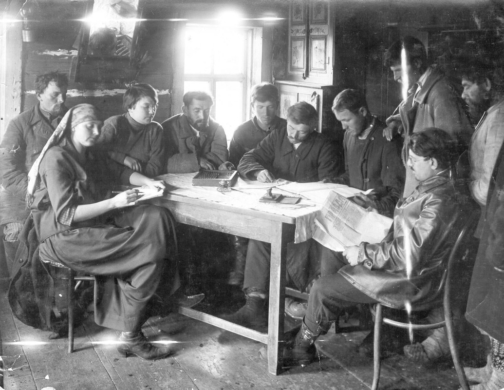 Large group of people sitting around a table indoors.