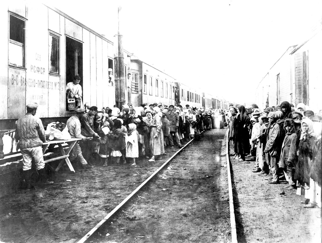Children lined up along train cars, receiving food
