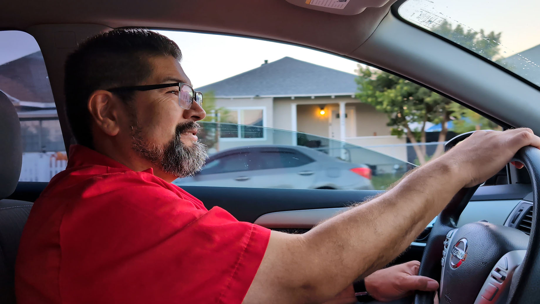 Man driving a car with the window down.