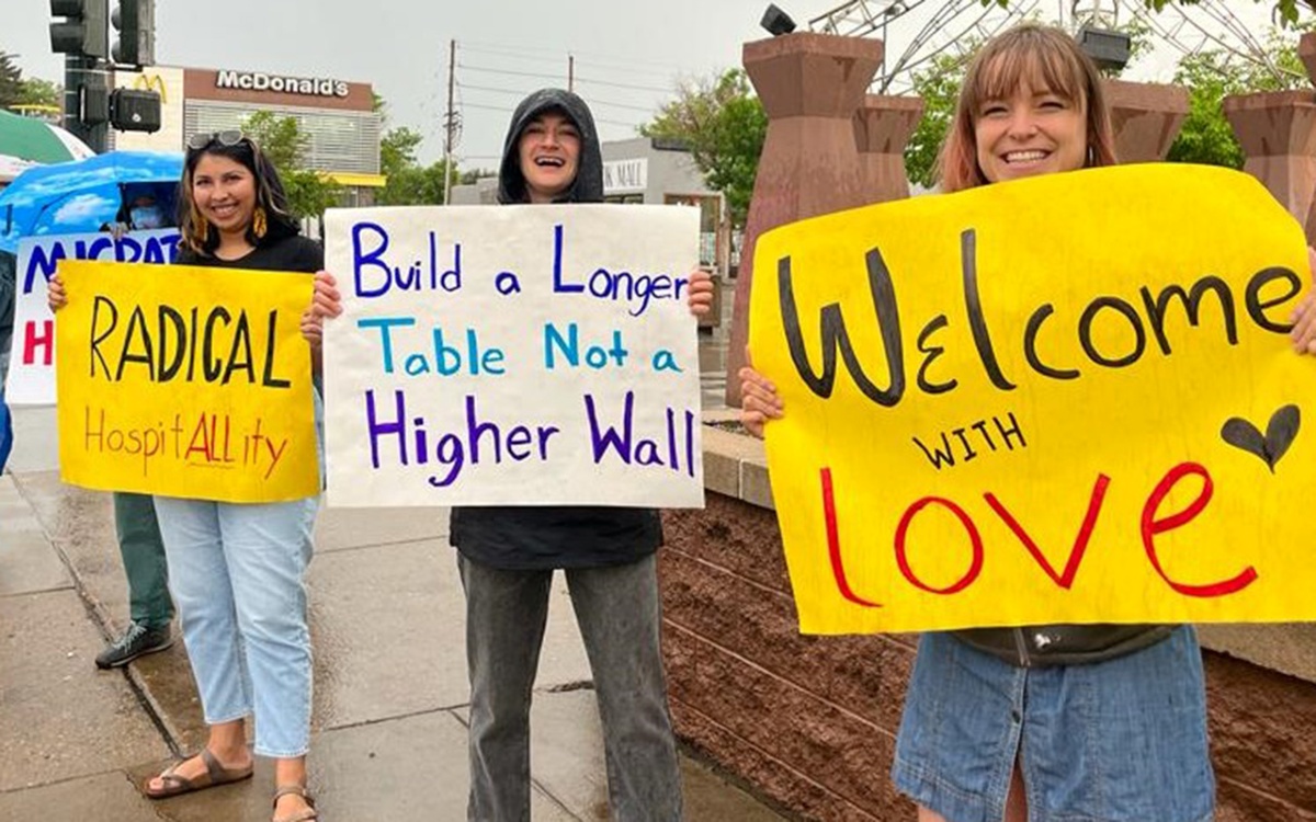 Demonstrators hold signs with slogans welcoming immigrants