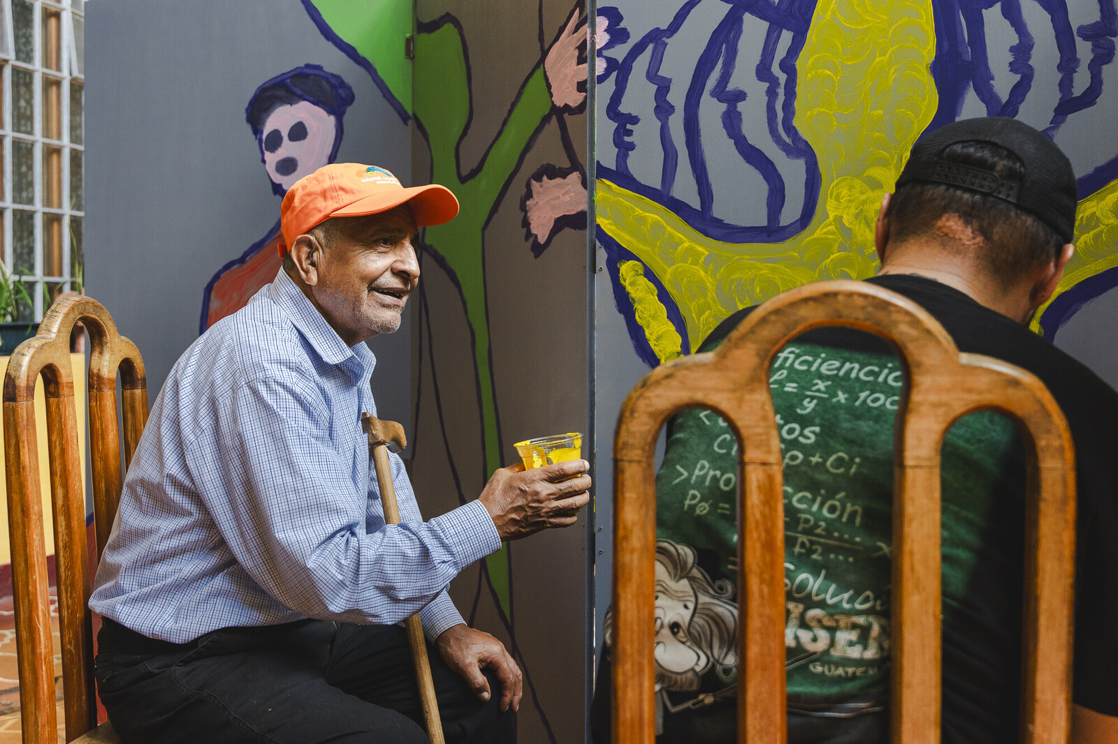 person holding a paint cup in front of a mural