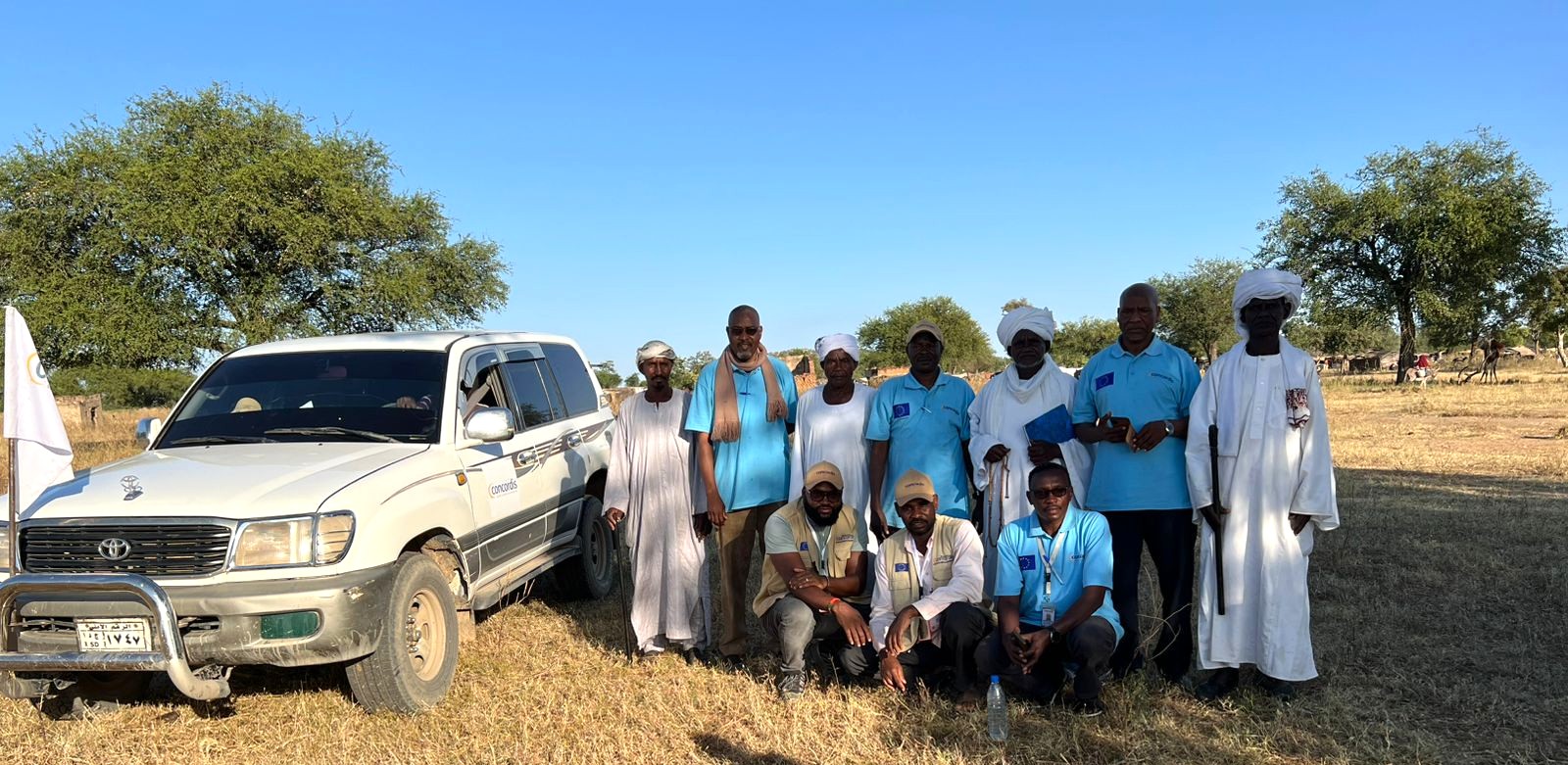 Concordis International staff take a group photo in South Darfur with their battered jeep